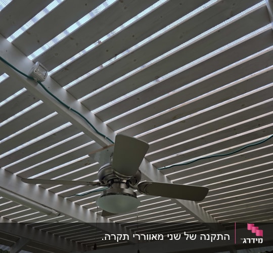 מאוורר תקרה מותקן על פרגולה עם חיווט חשמלי גלוי.